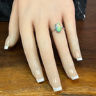 18kt white gold black opal ring worn on the hand, oval Australian black opal with diamond accents