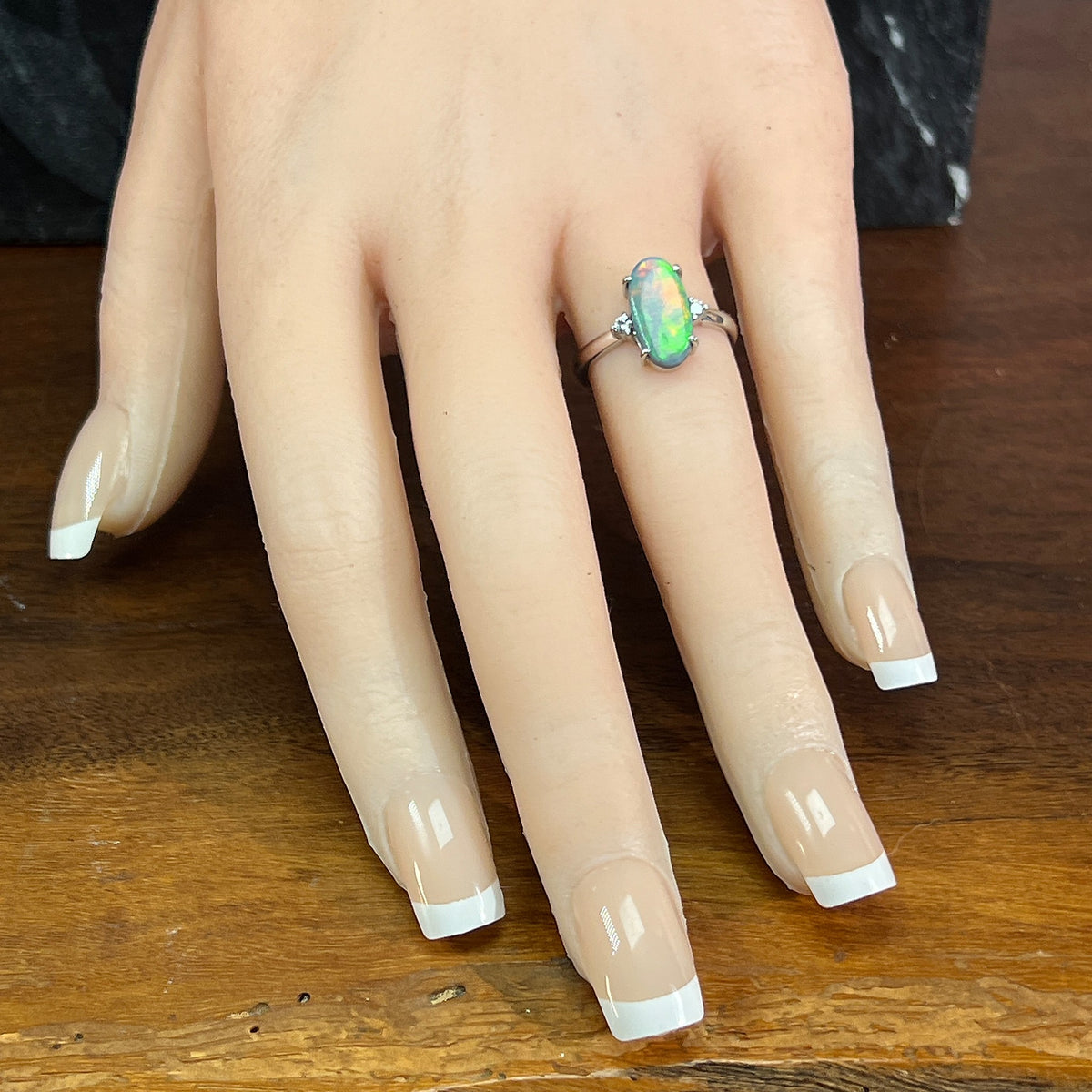 18kt white gold black opal ring worn on the hand, oval Australian black opal with diamond accents