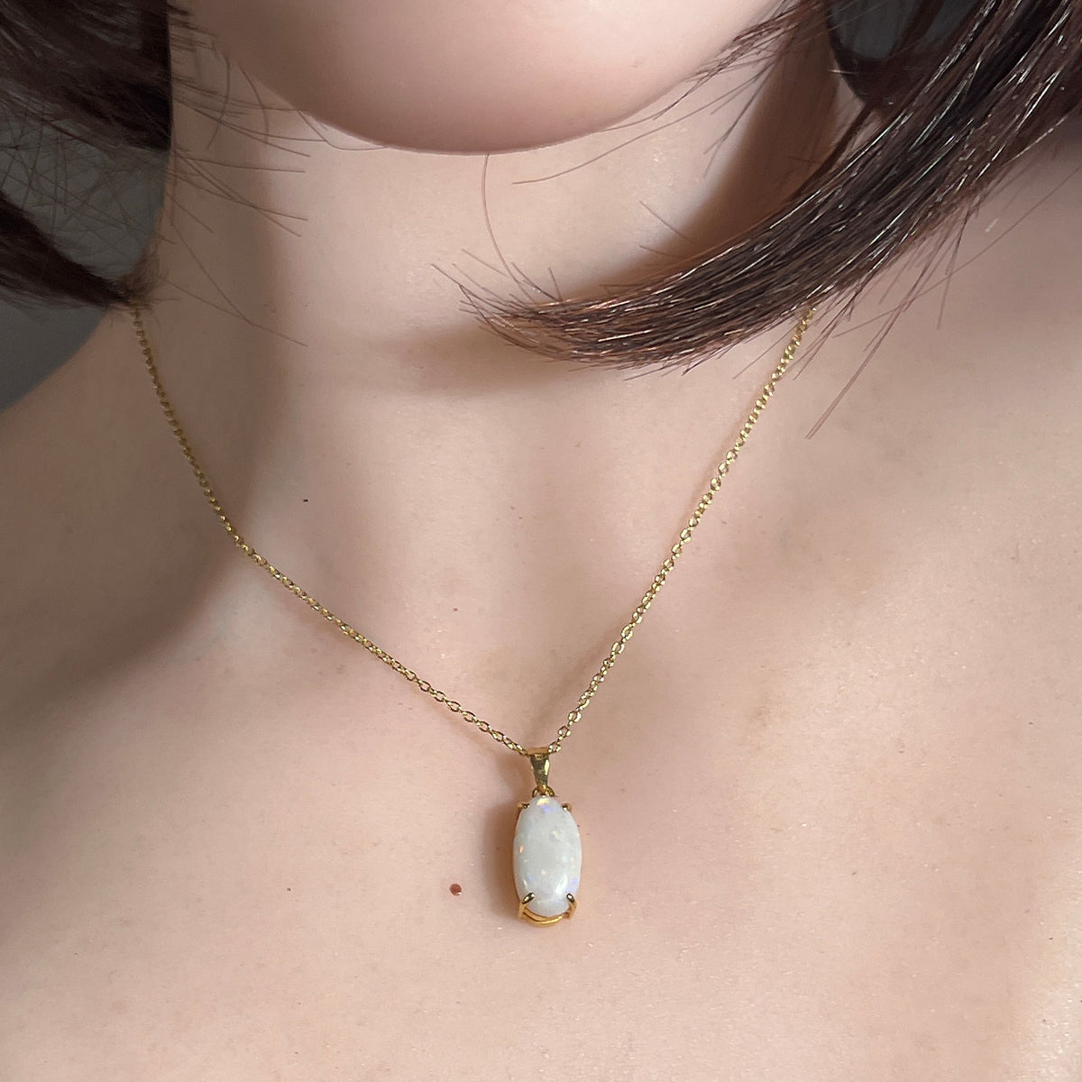 18kt yellow gold white opal pendant worn at the neckline, oval Australian white opal
