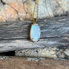 Close view of an oval Australian white opal in an 18kt yellow gold pendant, red and blue pinfire