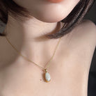 Oval Australian white opal pendant worn at the neck, 18kt yellow gold claw setting