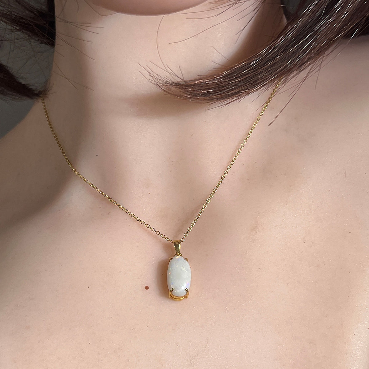 Woman wearing an 18kt yellow gold white opal pendant, 2.3ct oval Australian white opal