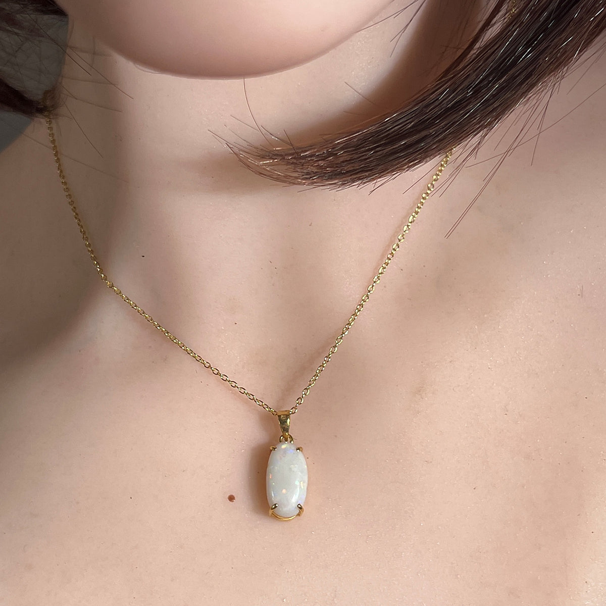White opal pendant worn close up, oval Australian white opal in 18kt yellow gold