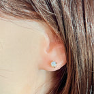 Round crystal opal stud earring worn in the ear