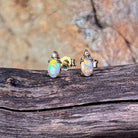 Oval crystal opal and diamond stud earrings in 9kt yellow gold on driftwood