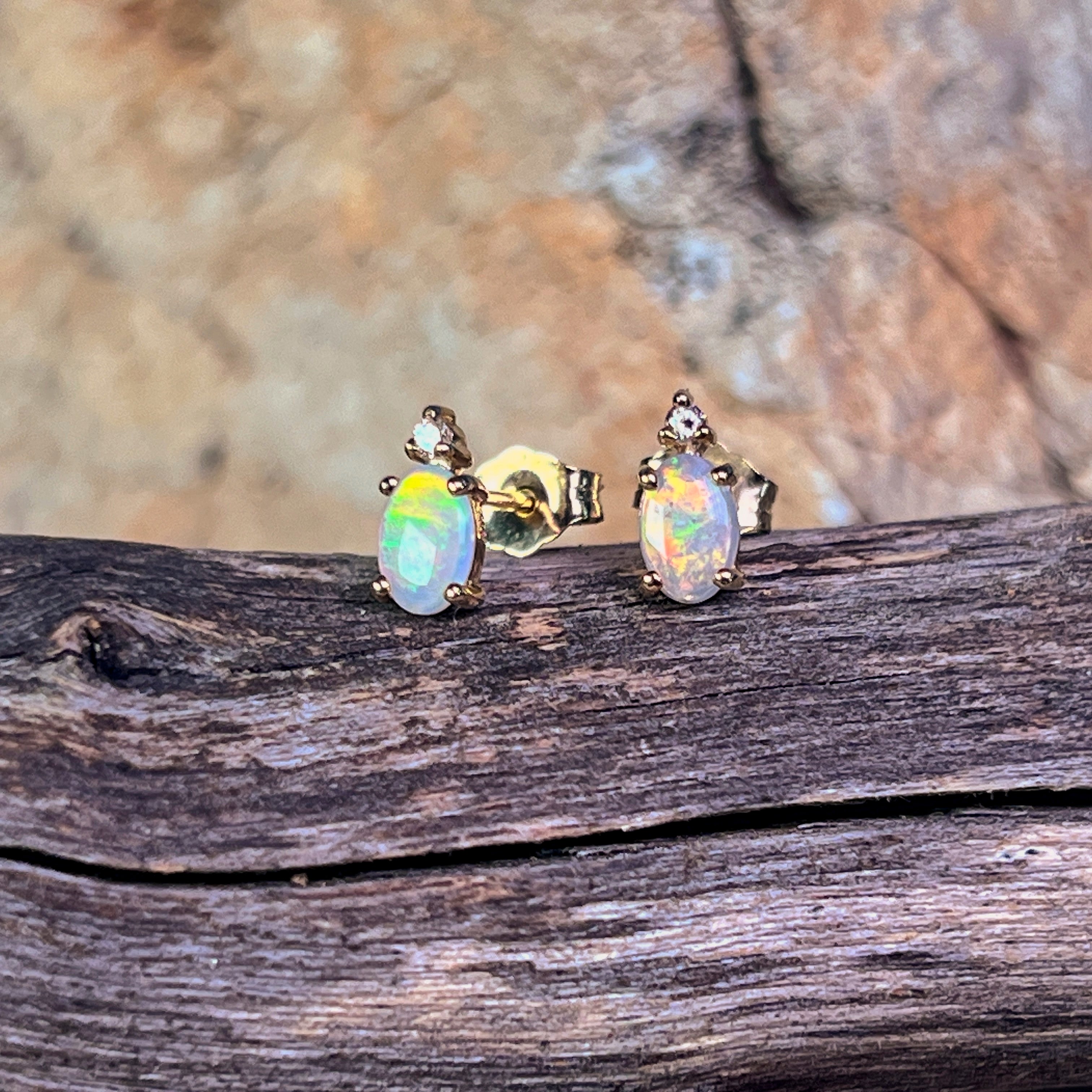 Oval crystal opal and diamond stud earrings in 9kt yellow gold on driftwood