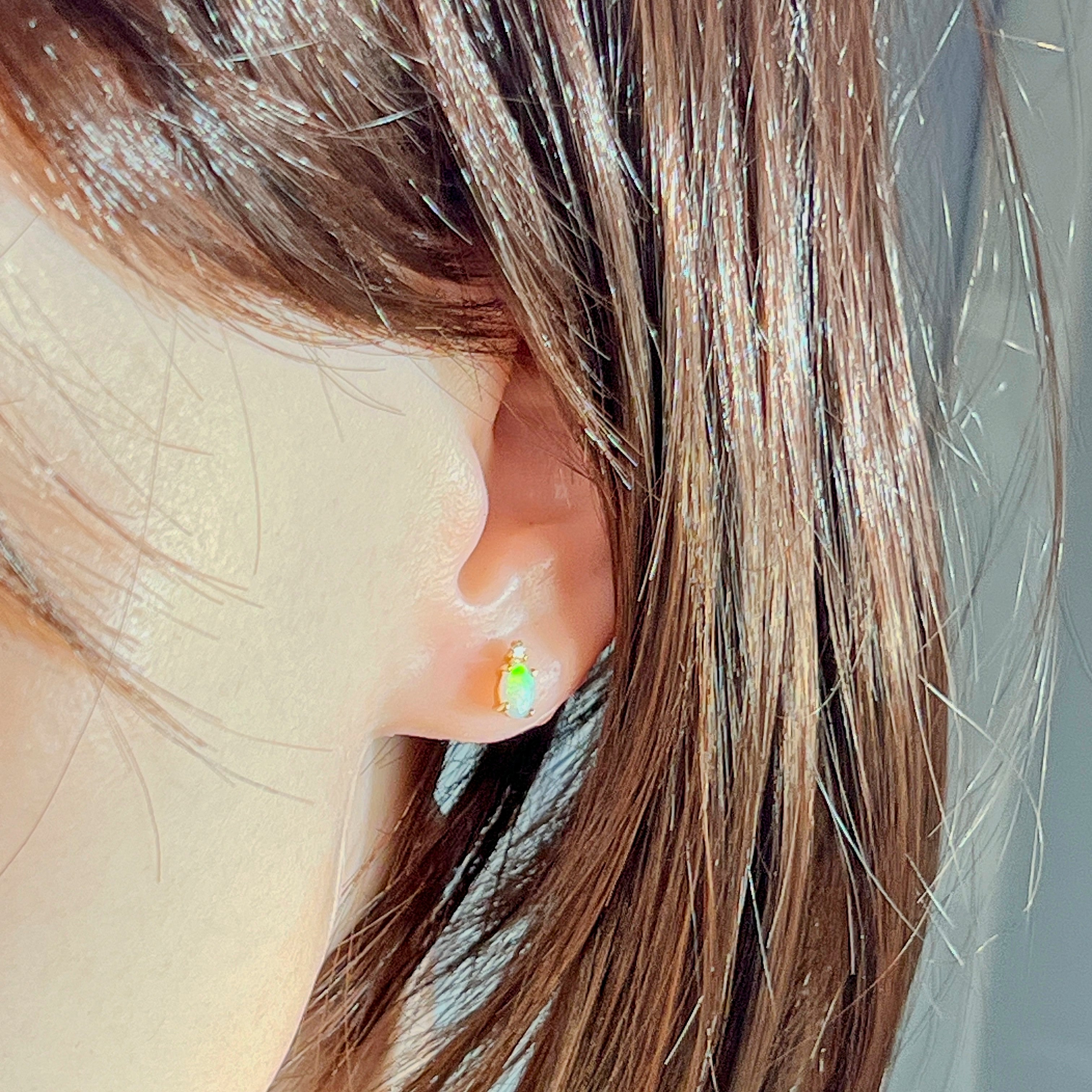 Crystal opal and diamond stud in the ear, showing scale against the lobe