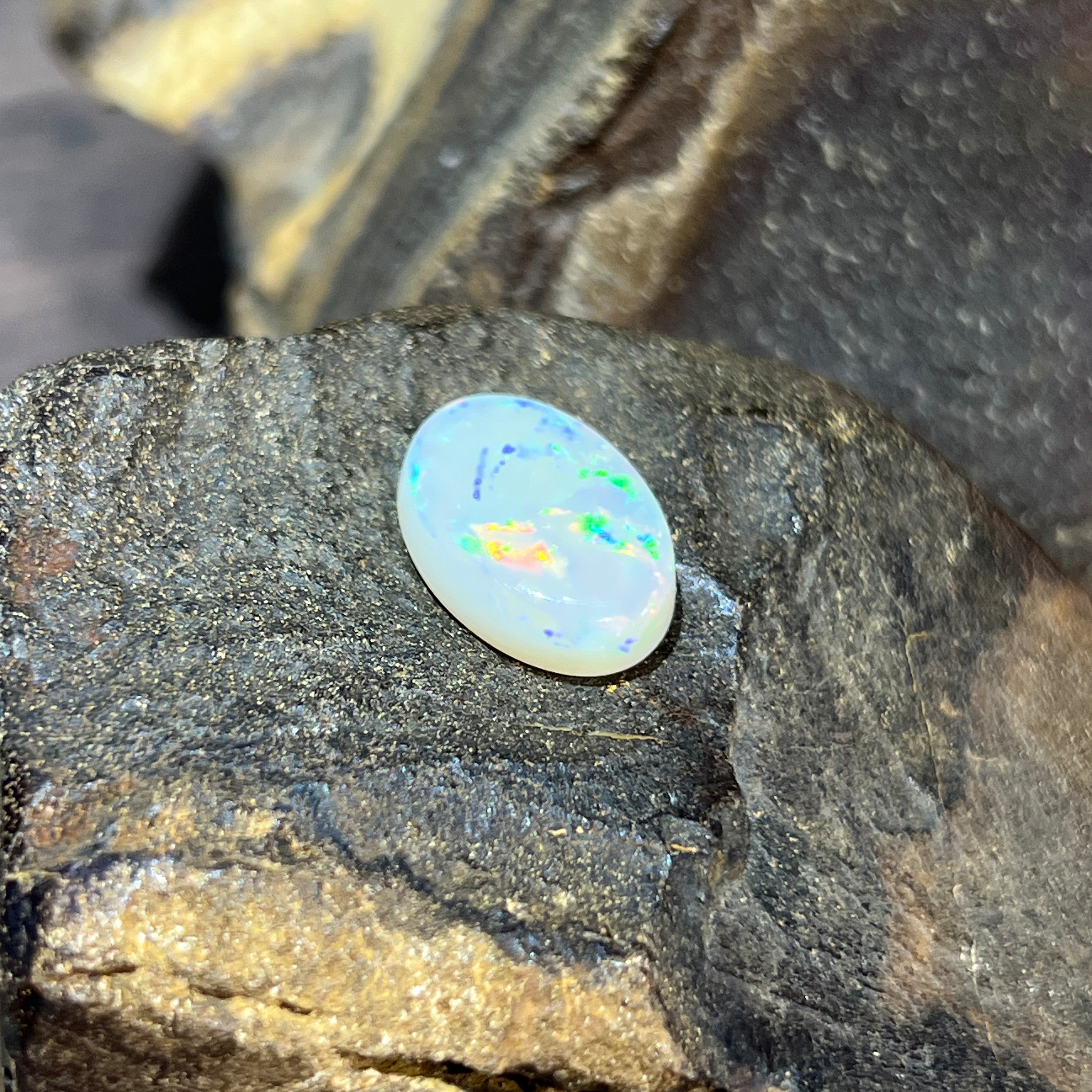 16x12mm white opal oval, bright green and blue flashes with a warm amber patch