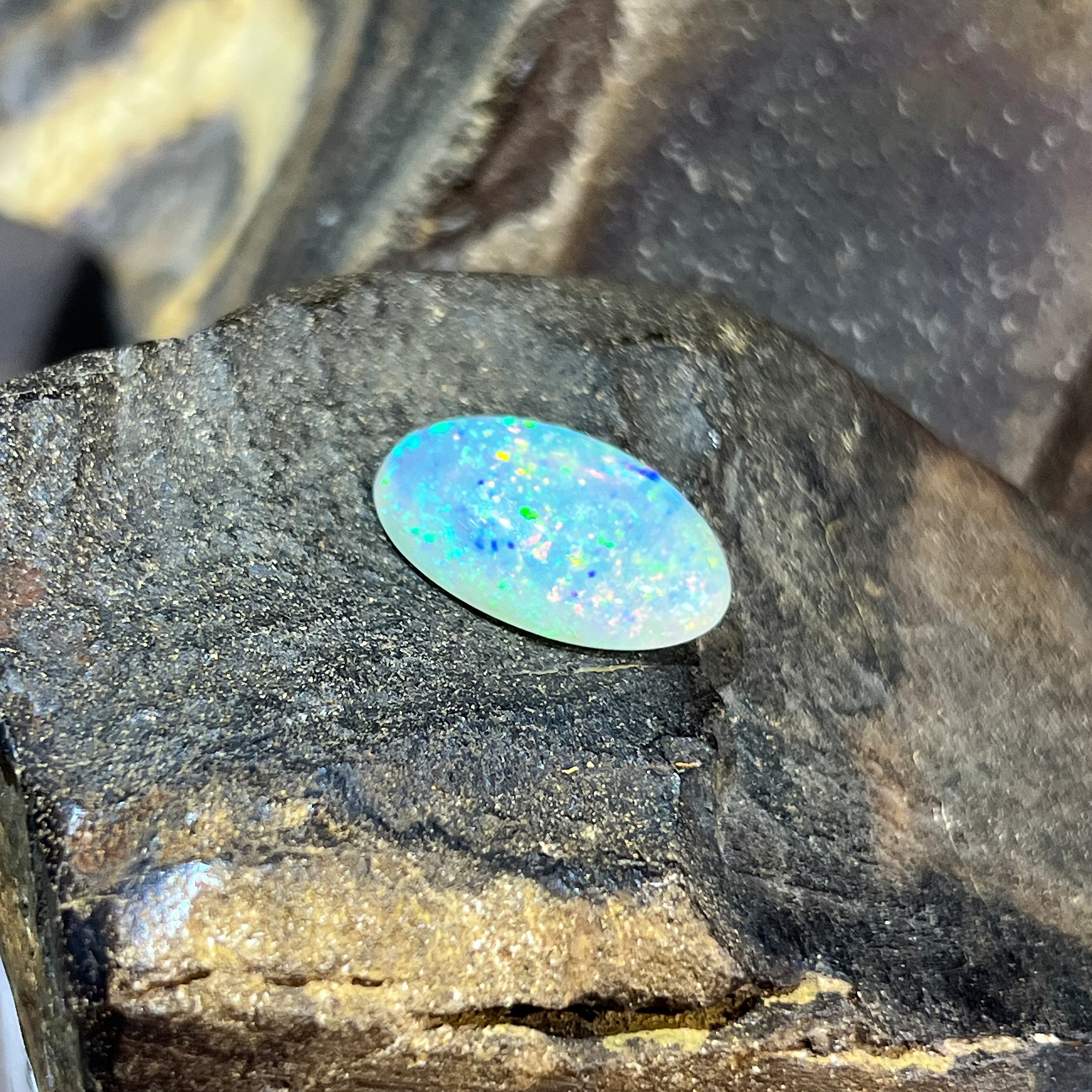 Angled view of the 18x11mm crystal opal, green and yellow flashes across its length