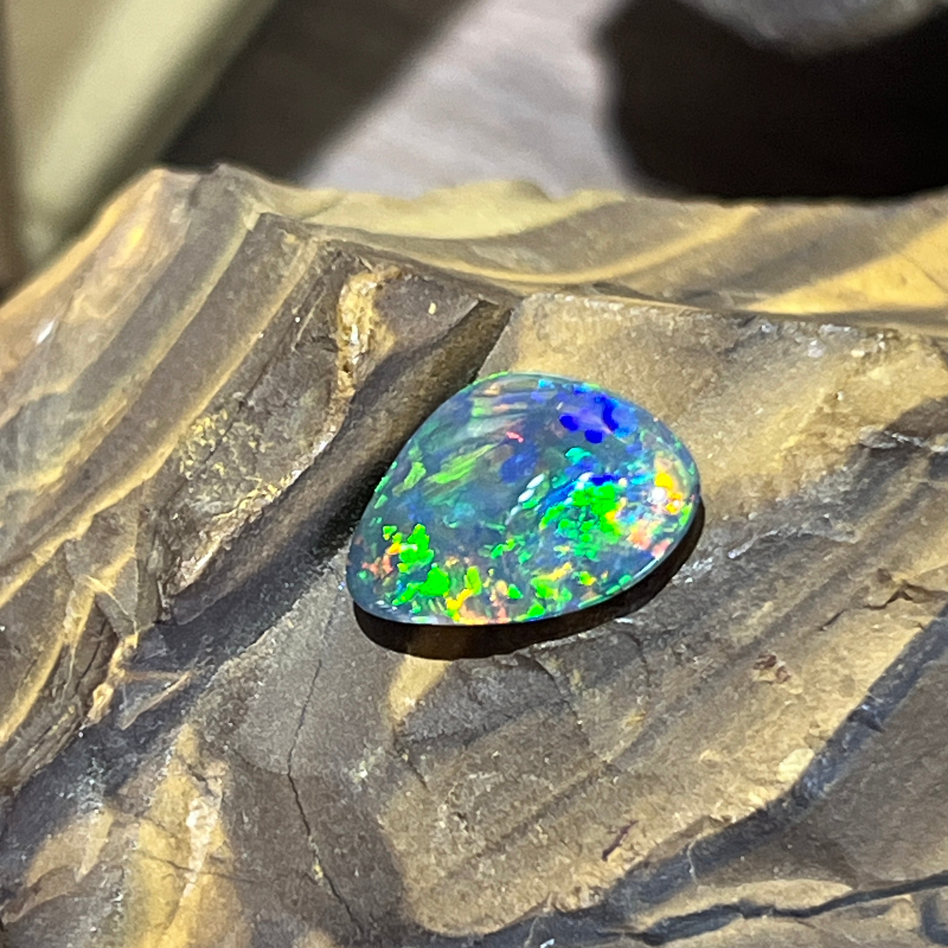 Australian black opal at a low angle, showing its dark body tone and cabochon dome