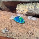 Loose 2.46ct freeform Australian opal doublet resting on weathered driftwood