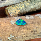 Angled view of the freeform Australian opal doublet with green and orange fire on a blue base
