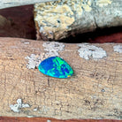 Freeform opal doublet angled to catch green play-of-colour on driftwood