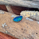 Angled view of the drop shaped Australian opal doublet with green pinfire on a blue base