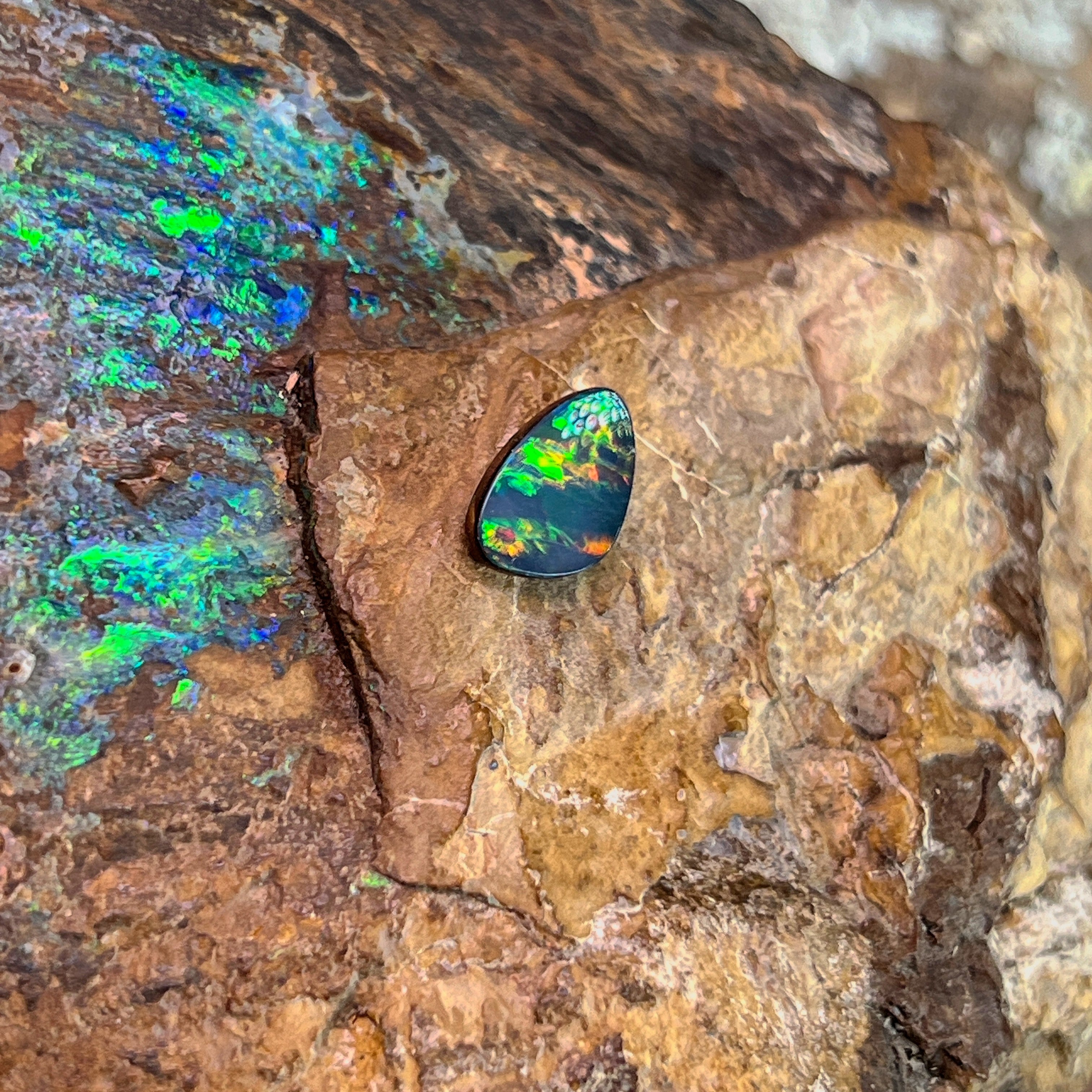 Green and gold play-of-colour across a 1.5ct freeform Australian opal doublet on rock