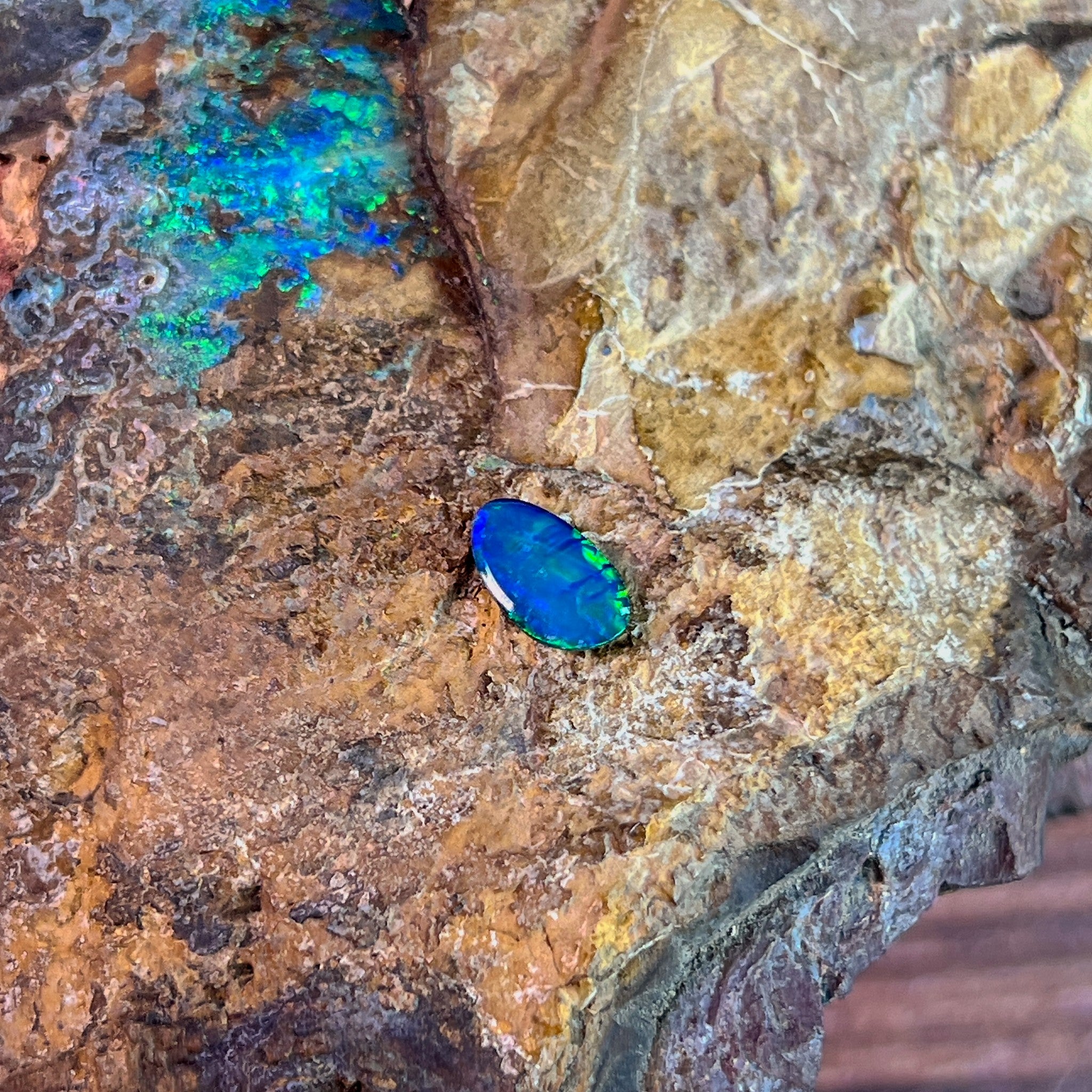 Blue and green play-of-colour in a 0.65ct Australian opal doublet, 9x5.3mm, on rock