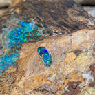 Red and green flashes across an elongated 0.88ct Australian opal doublet on weathered rock