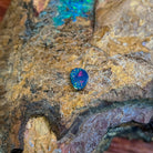 Rose and green pinfire in a freeform 0.78ct Australian opal doublet resting on rock