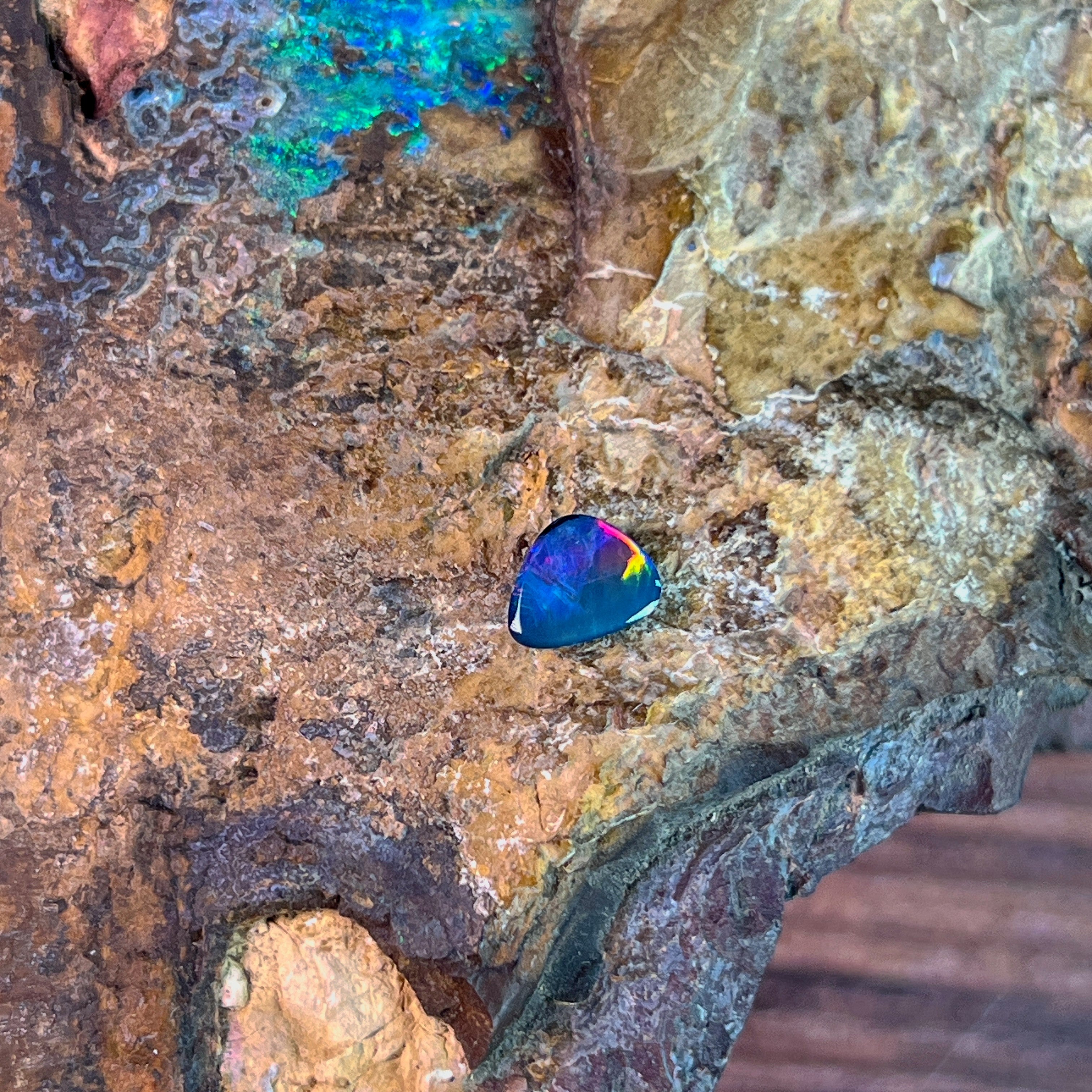 Pink and yellow fire in a 0.70ct Australian opal doublet, 7.4x5.9mm, on weathered rock
