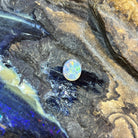 Solid Australian black opal 0.85ct, oval 8.2x6.8mm, red, orange and yellow flashes on a grey base, loose stone on rock