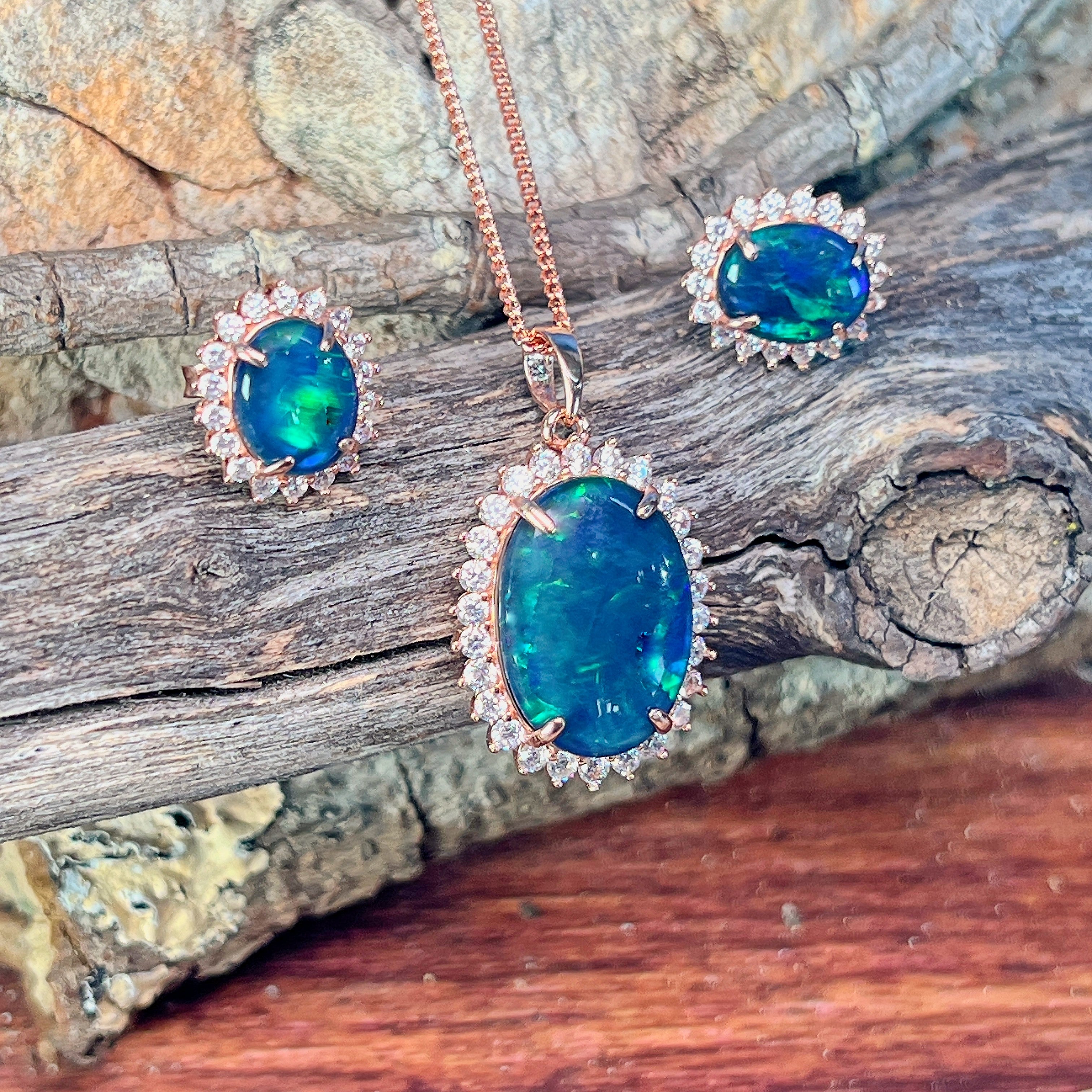 Opal triplet halo pendant and 10x8mm earrings in rose gold-plated silver against driftwood
