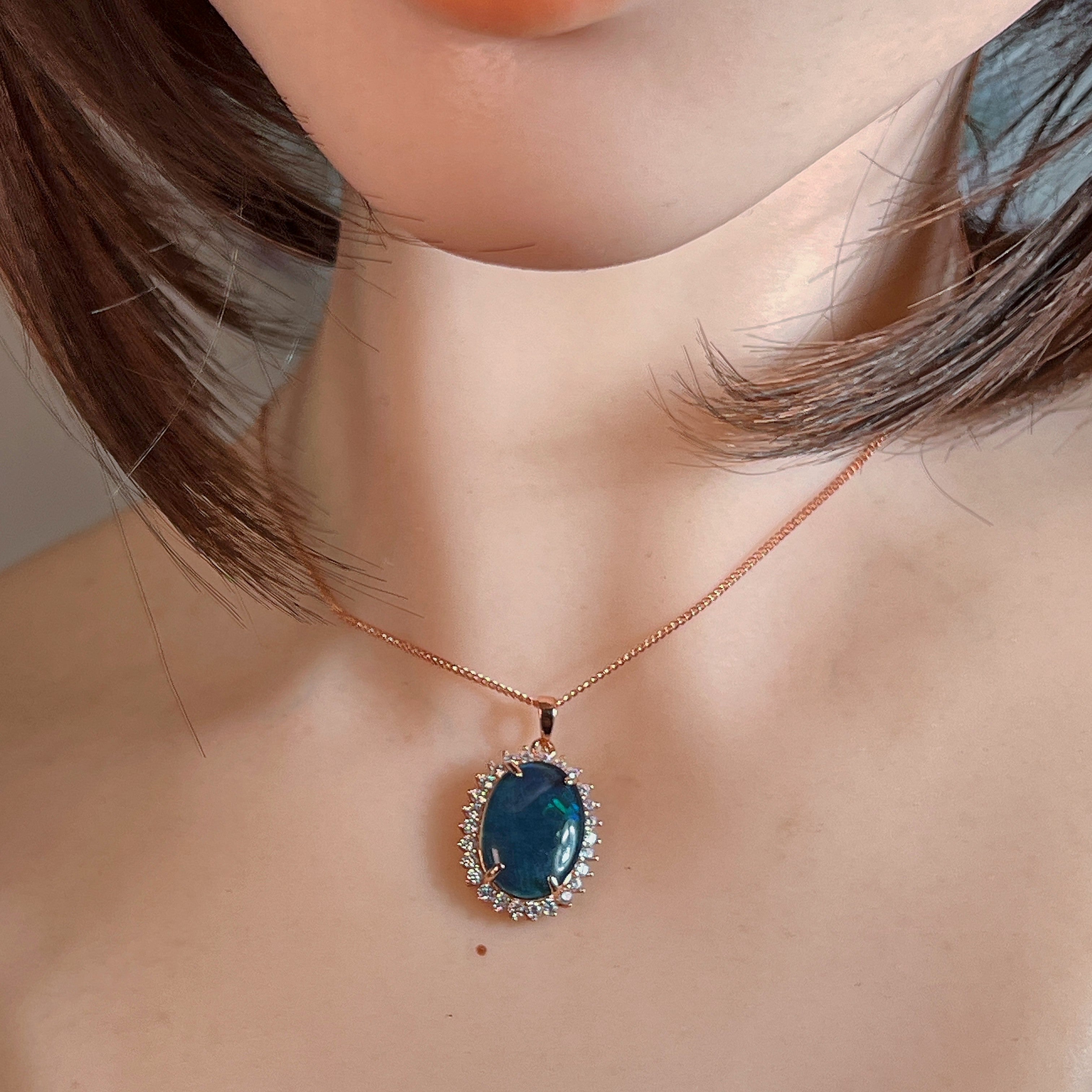 Rose gold-plated silver opal triplet halo pendant worn at the neckline, close view