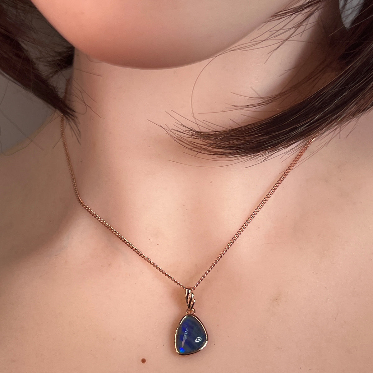 11 x 8mm freeform Australian opal triplet pendant worn at the neck, rose gold-plated silver
