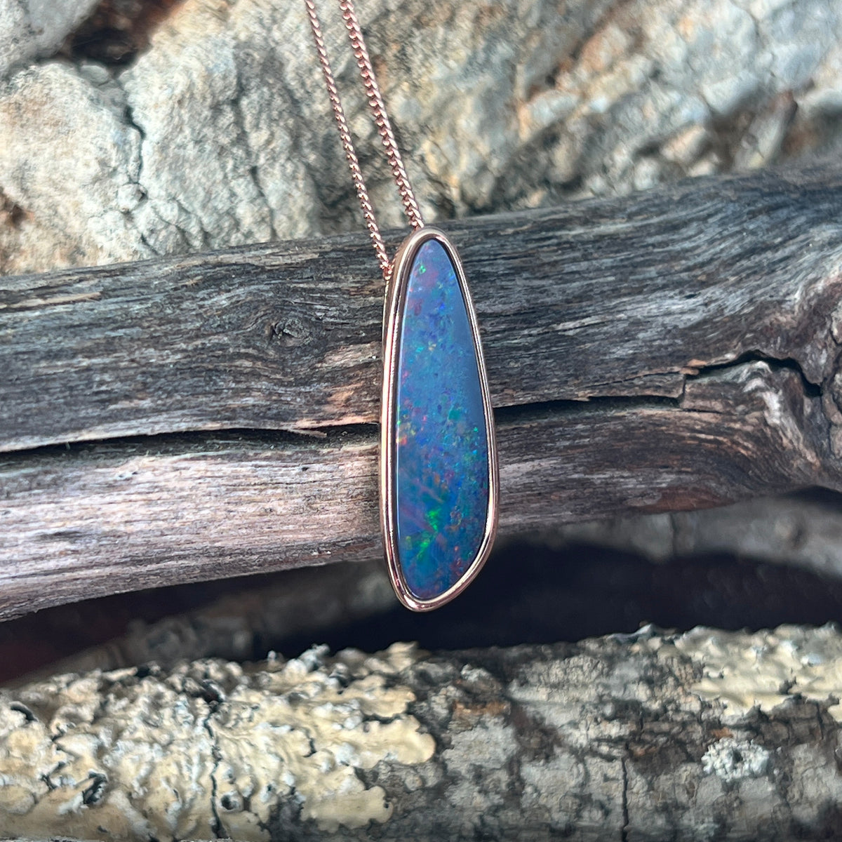 red, blue, yellow and green play-of-colour in a 27 x 8mm freeform Australian opal doublet pendant