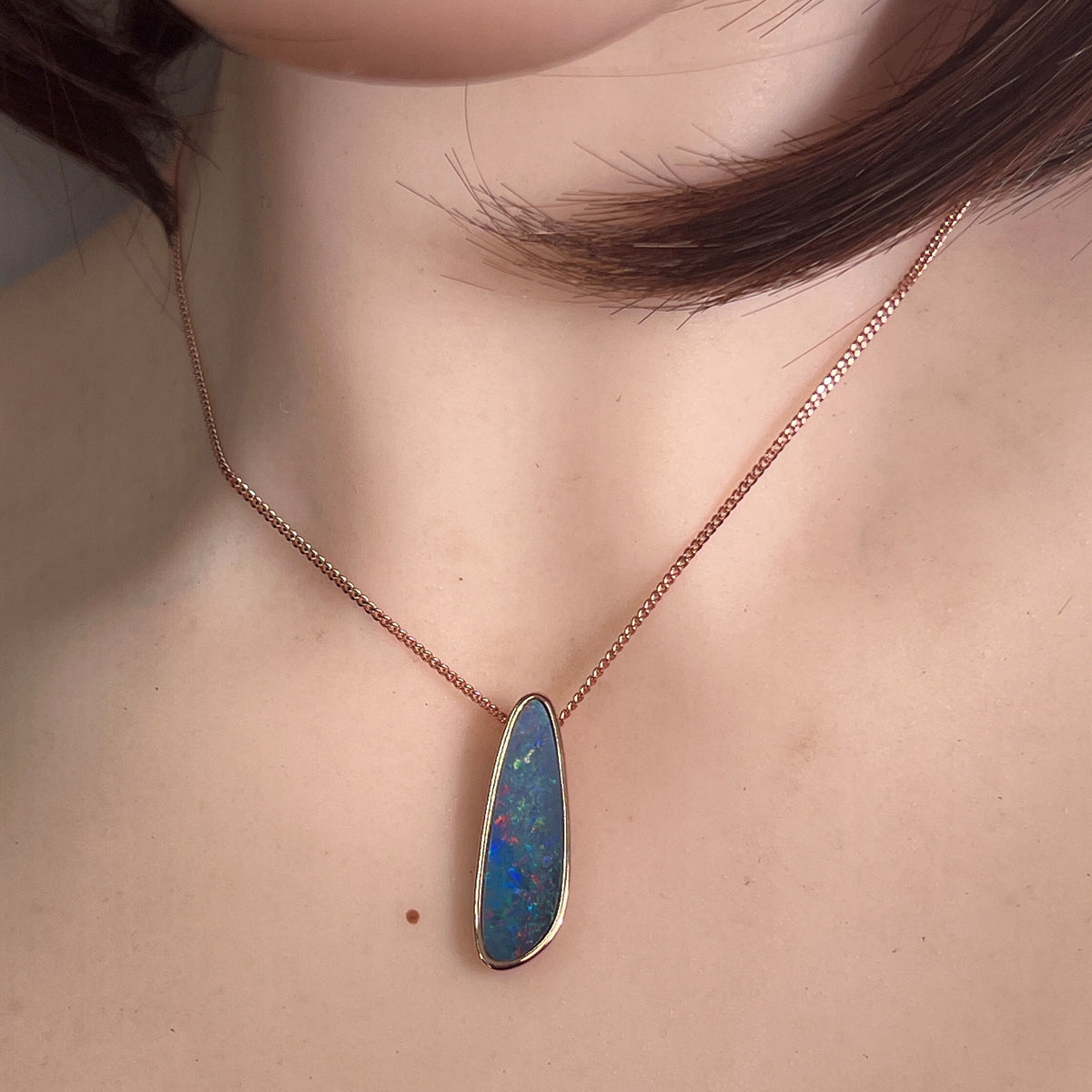 Australian opal doublet pendant worn at the neck, red, blue, yellow and green play-of-colour