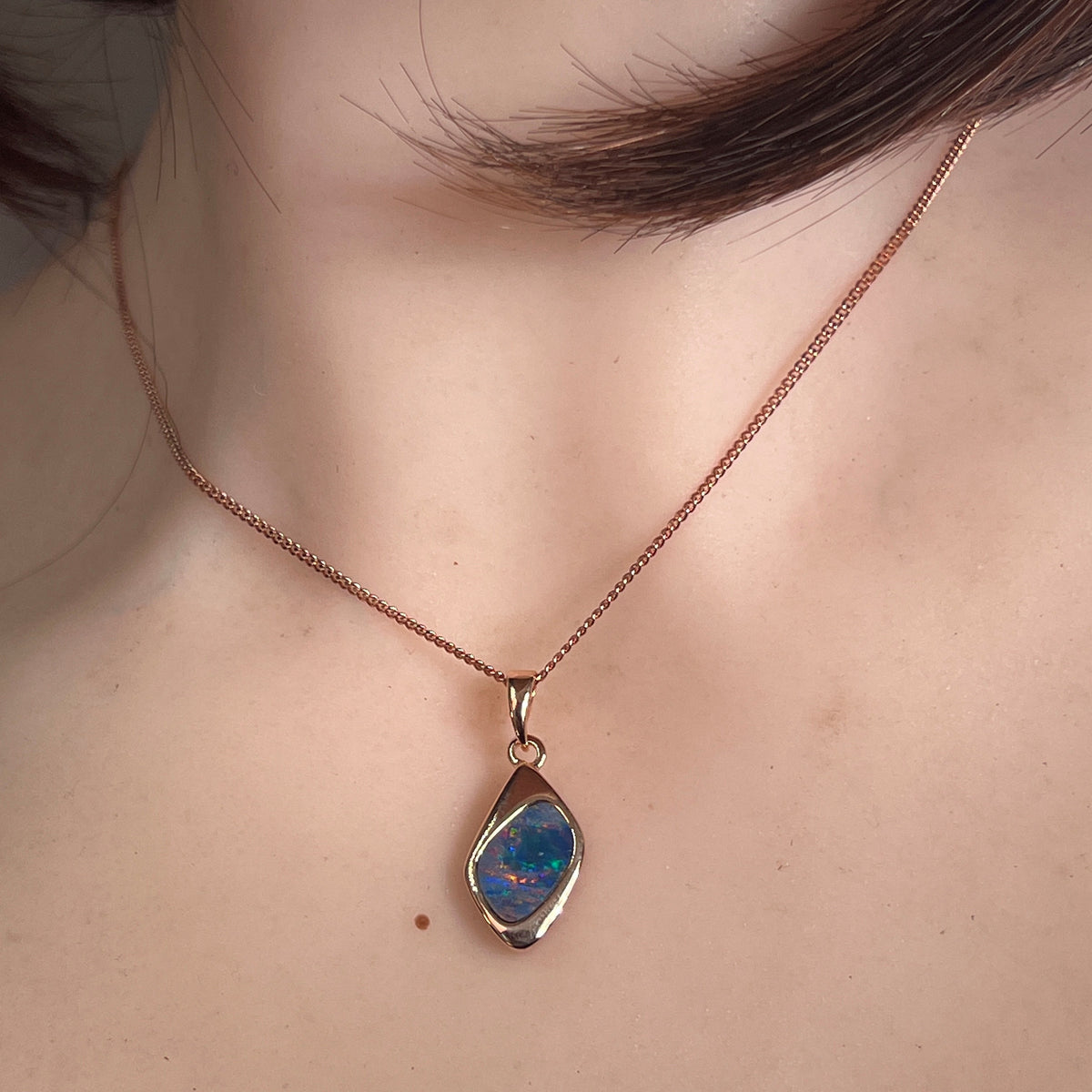 12 x 9mm freeform Australian opal doublet pendant worn at the neck, rose gold-plated silver