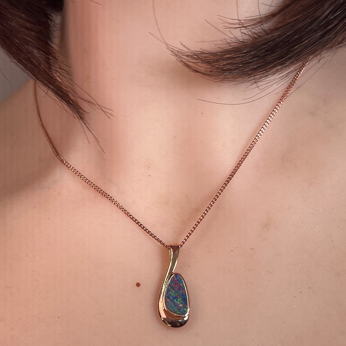 12 x 7mm freeform Australian opal doublet pendant worn at the neck, rose gold-plated silver
