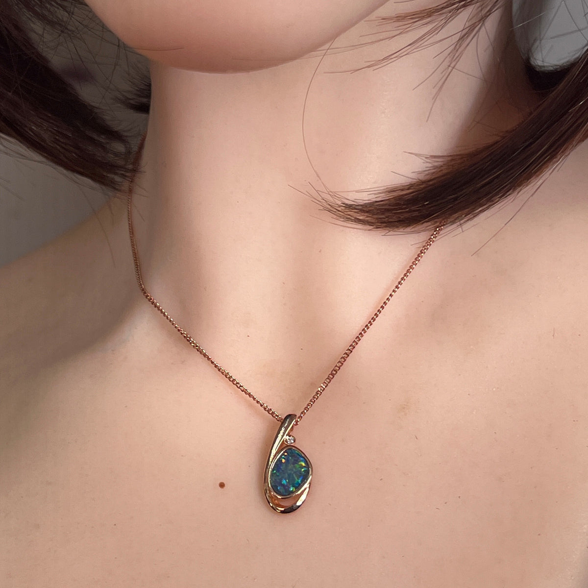 Worn Australian opal doublet pendant in rose gold-plated silver, green, red and blue, 11 x 8mm