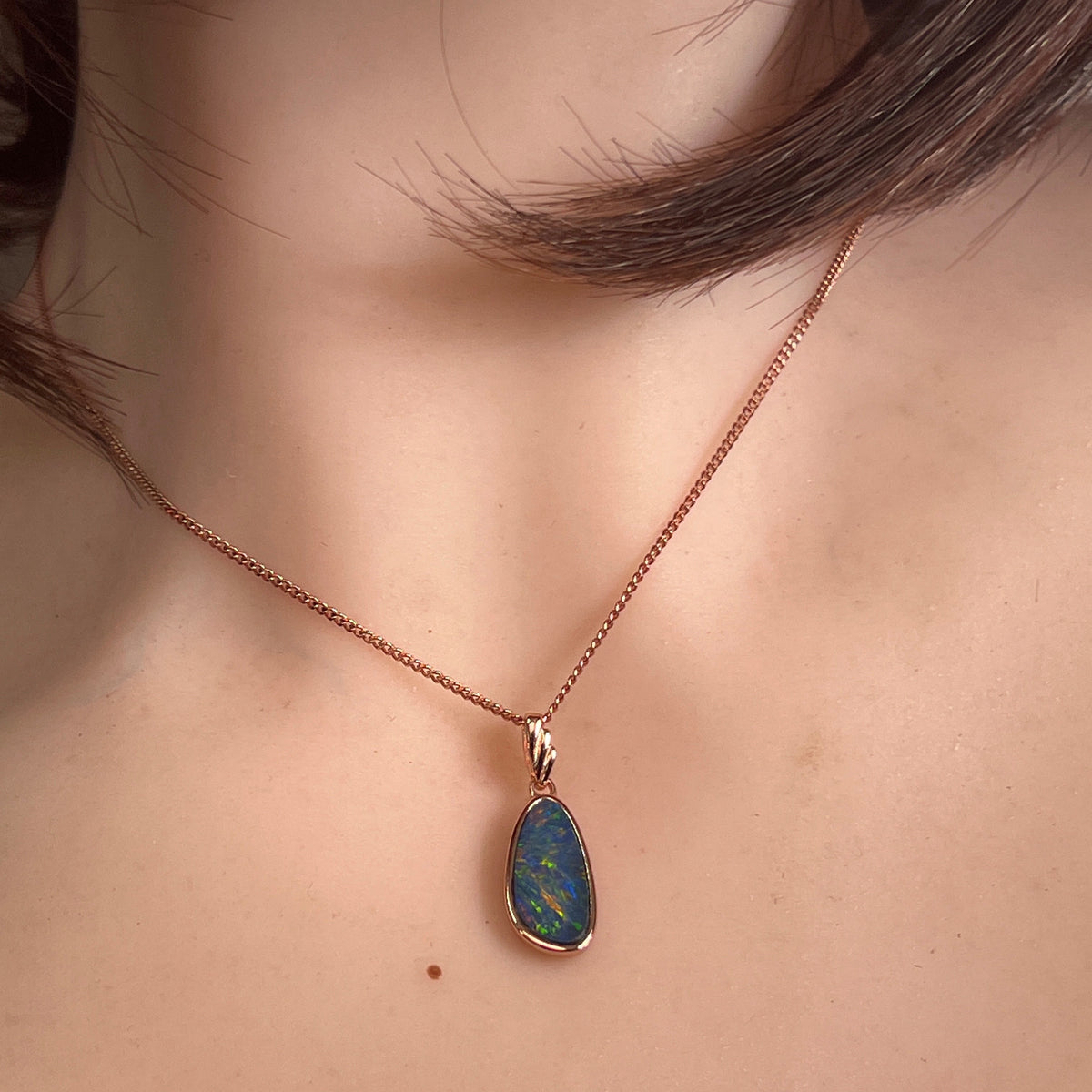 Australian opal doublet pendant worn, 15 x 7.5mm marquise stone in rose gold-plated silver
