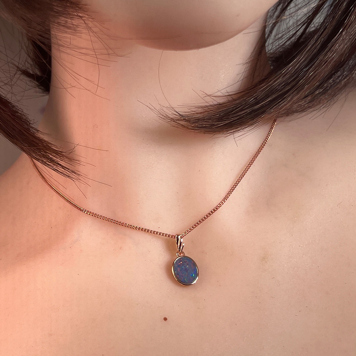 Worn Australian opal doublet pendant in rose gold-plated silver, red, blue, green and violet, 15 x 7.5mm