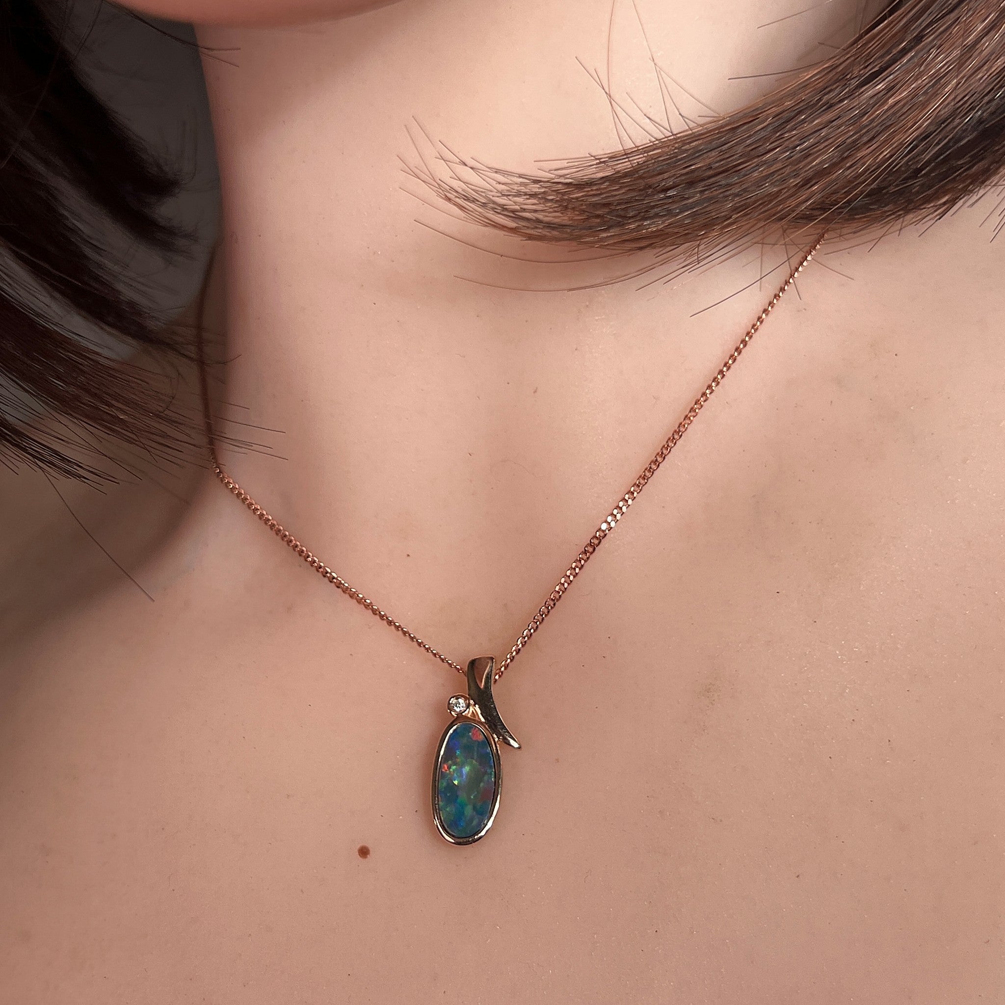13 x 7mm oval Australian opal doublet pendant worn at the neck, rose gold-plated silver