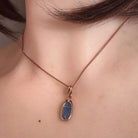 12 x 6mm oval Australian opal doublet pendant worn at the neck, rose gold-plated silver