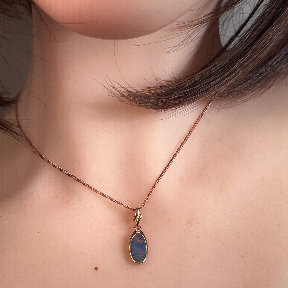 Worn Australian opal doublet pendant in rose gold-plated silver, red and blue, 12 x 6mm