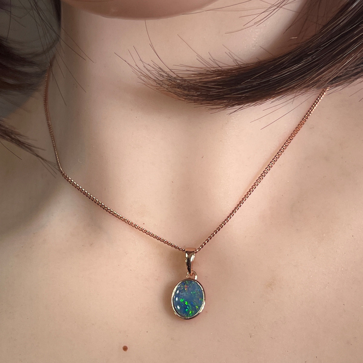 oval Australian opal doublet pendant in rose gold-plated silver, worn at the neck