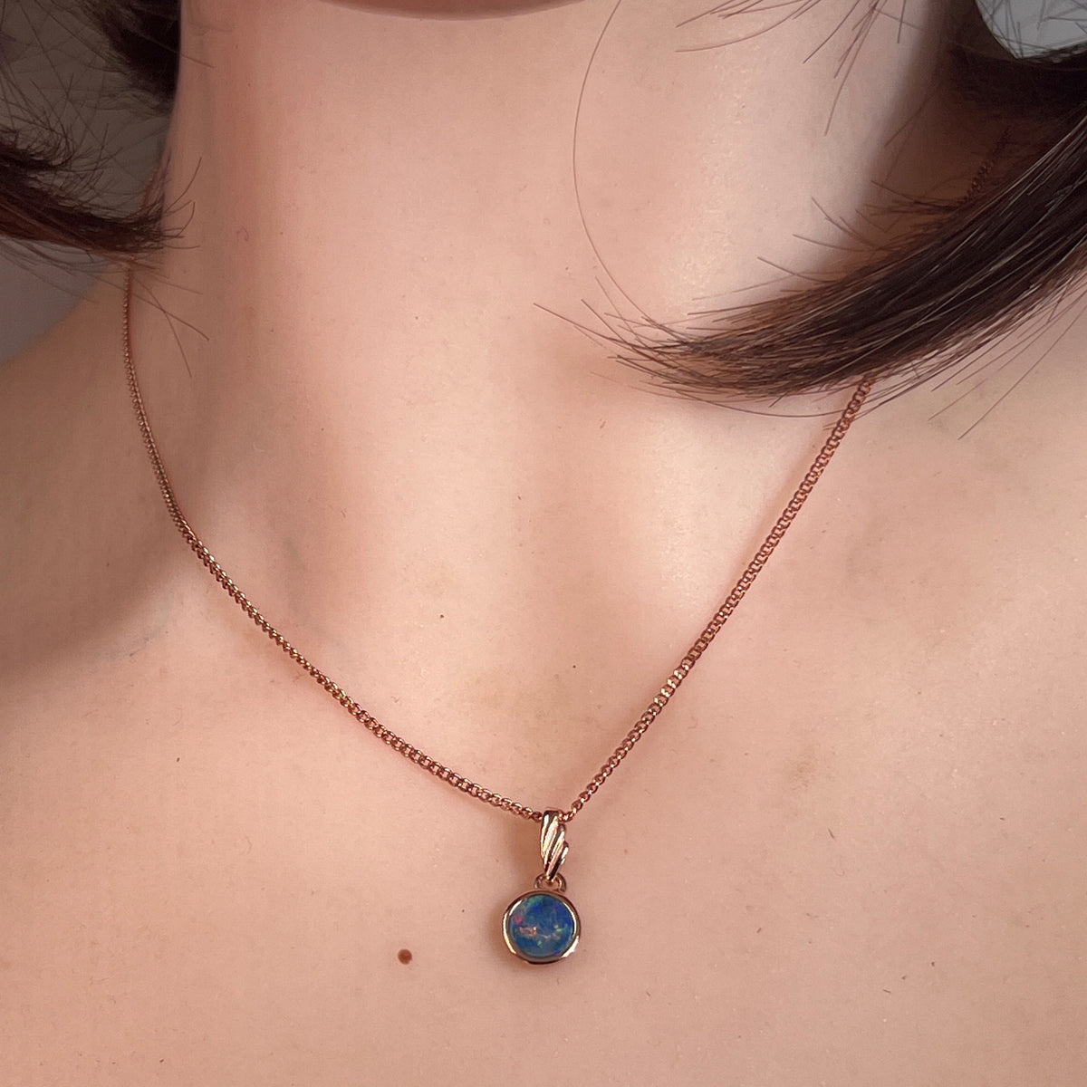 round Australian opal doublet pendant in rose gold-plated silver, worn at the neck