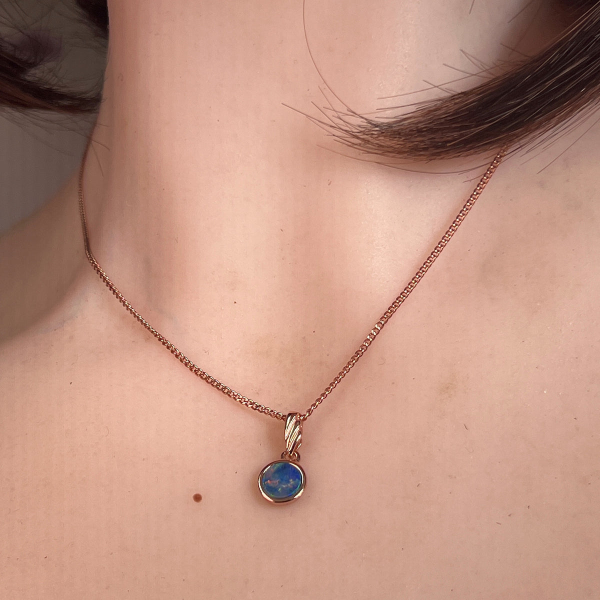6mm round Australian opal doublet pendant worn at the neck, rose gold-plated silver