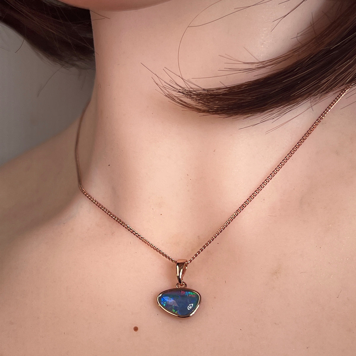 12 x 8mm freeform Australian opal triplet pendant worn at the neck, yellow gold-plated silver