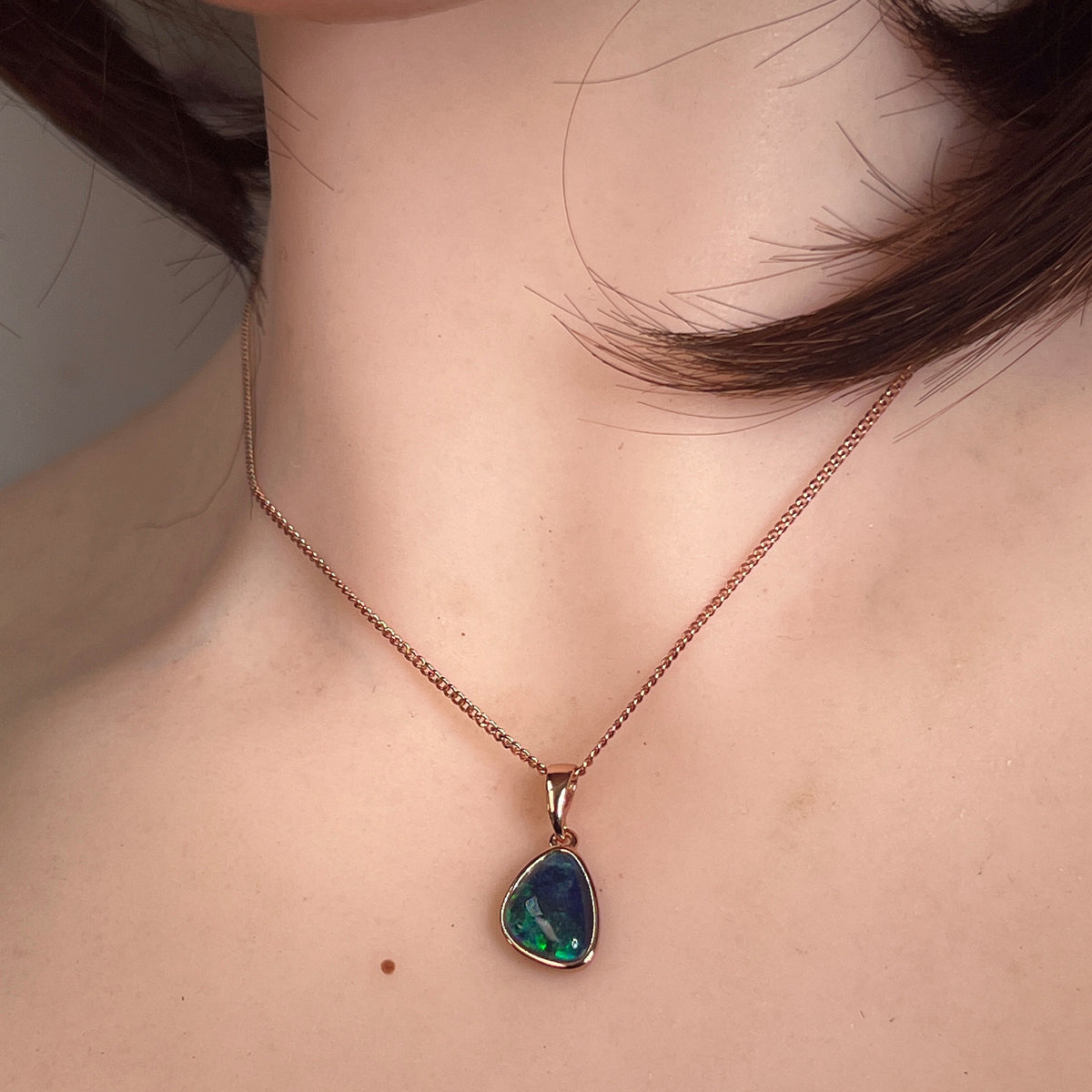 12 x 8mm freeform Australian opal triplet pendant worn at the neck, rose gold-plated silver