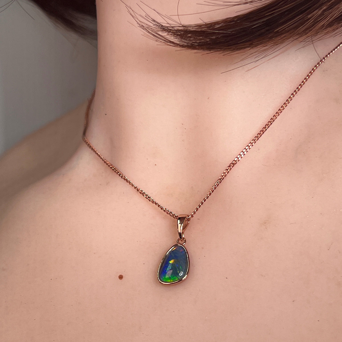 freeform Australian opal triplet pendant worn, rose gold-plated silver, red, green and blue