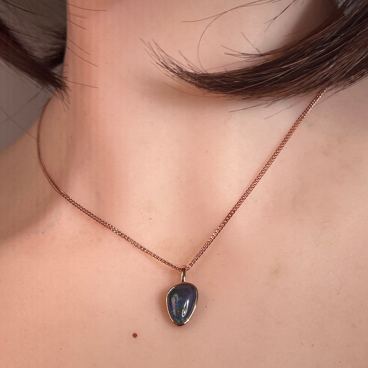 Australian opal triplet pendant worn, 12 x 8mm freeform stone in rose gold-plated silver