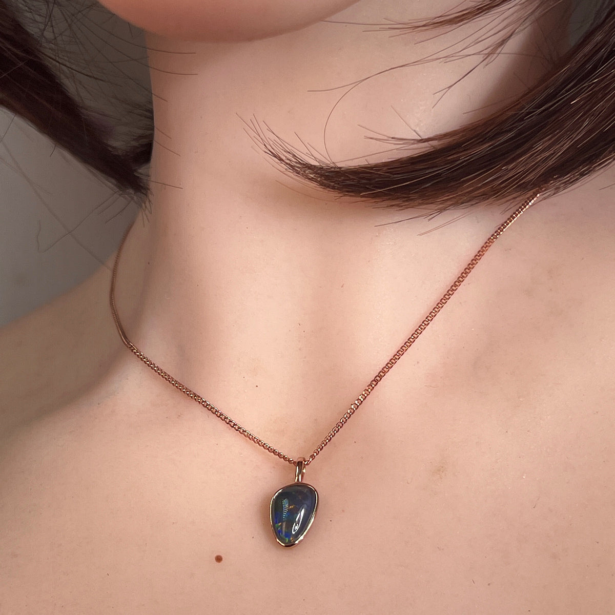 12 x 8mm Australian opal triplet pendant worn at the neck, rose gold-plated silver, red, green and blue