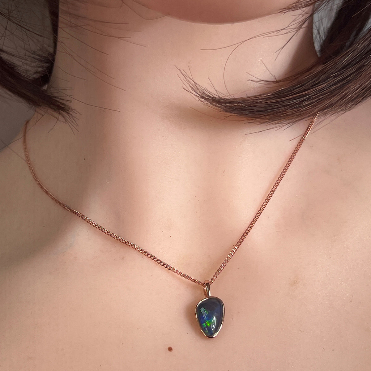 bezel-set Australian opal triplet pendant worn at the neck, 12 x 8mm freeform stone, rose gold-plated silver