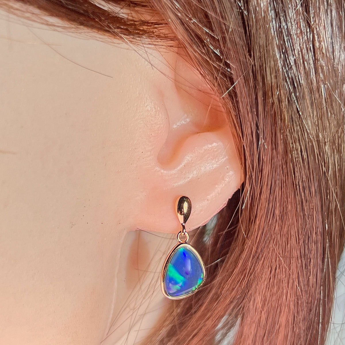 triangular Australian opal triplet earrings in rose gold-plated silver, worn on the ear
