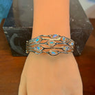Sterling silver opal wave bangle worn on the wrist