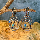 Sterling silver Australian opal circle earrings resting on a branch