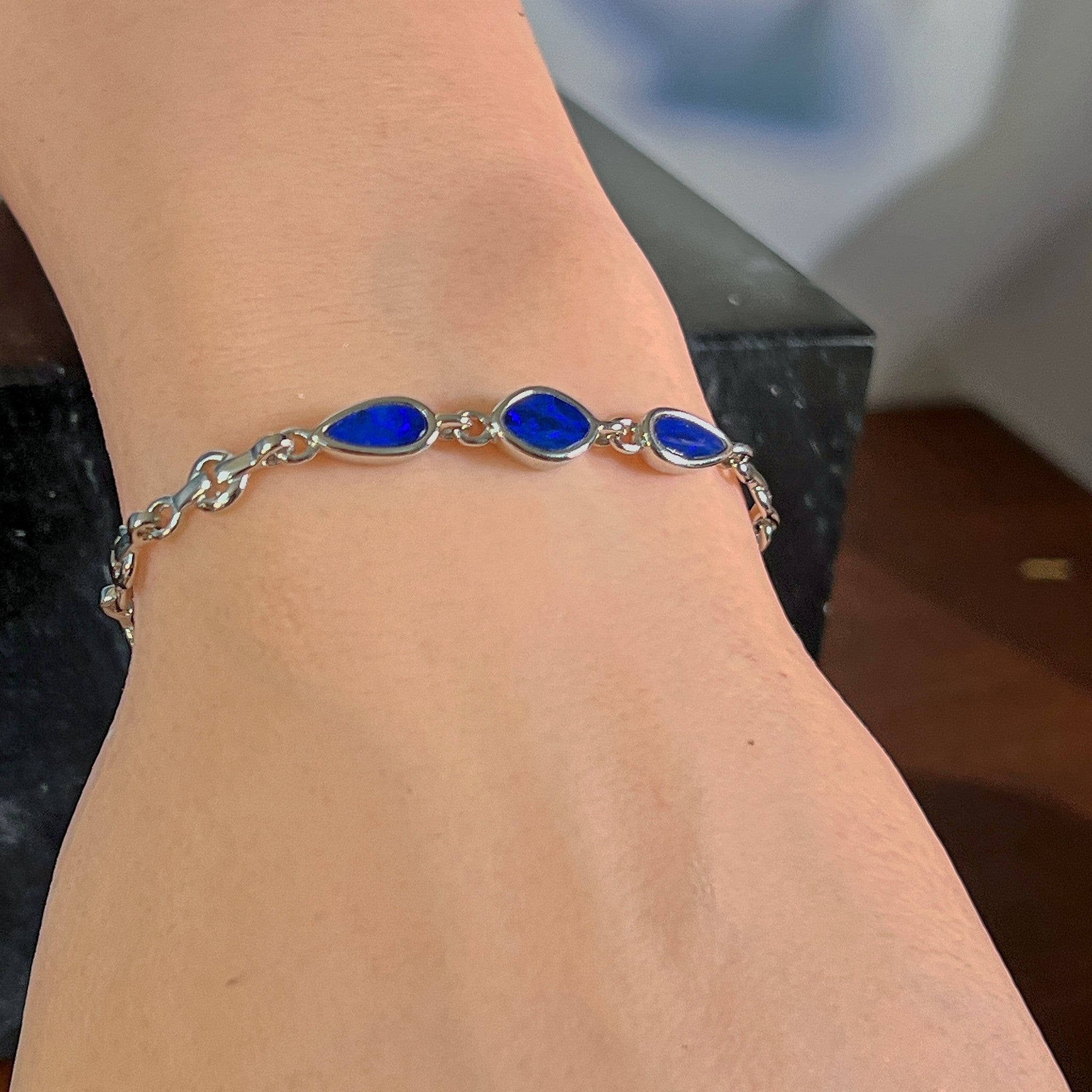 Sterling silver bracelet with three opal doublets worn on the wrist, showing the length of the chain